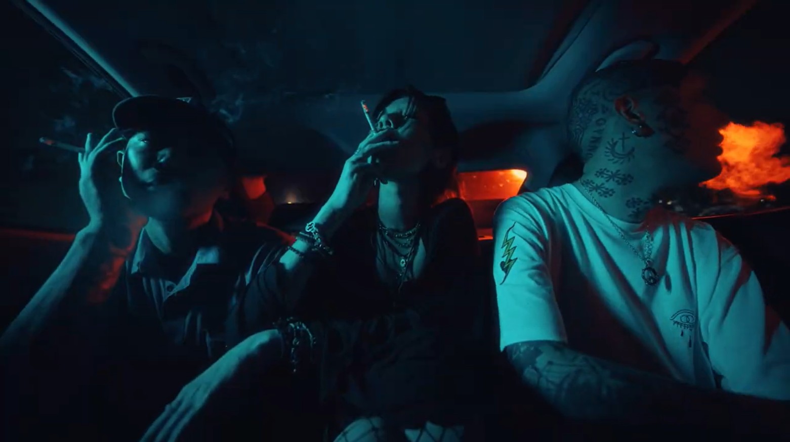 Three people sharing cannabis inside a car at night